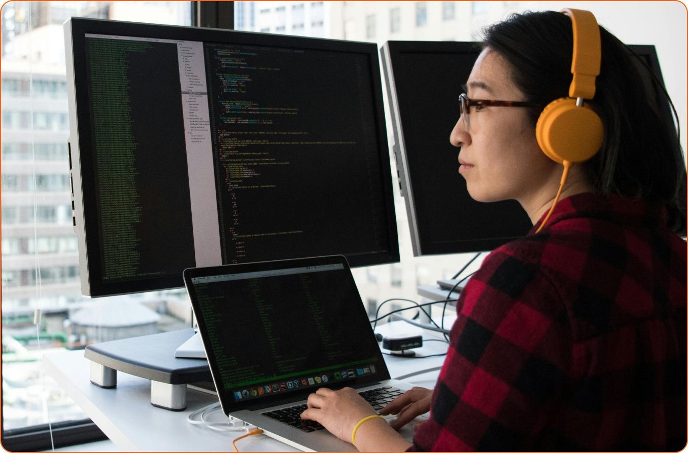 Woman with headphones coding on computer